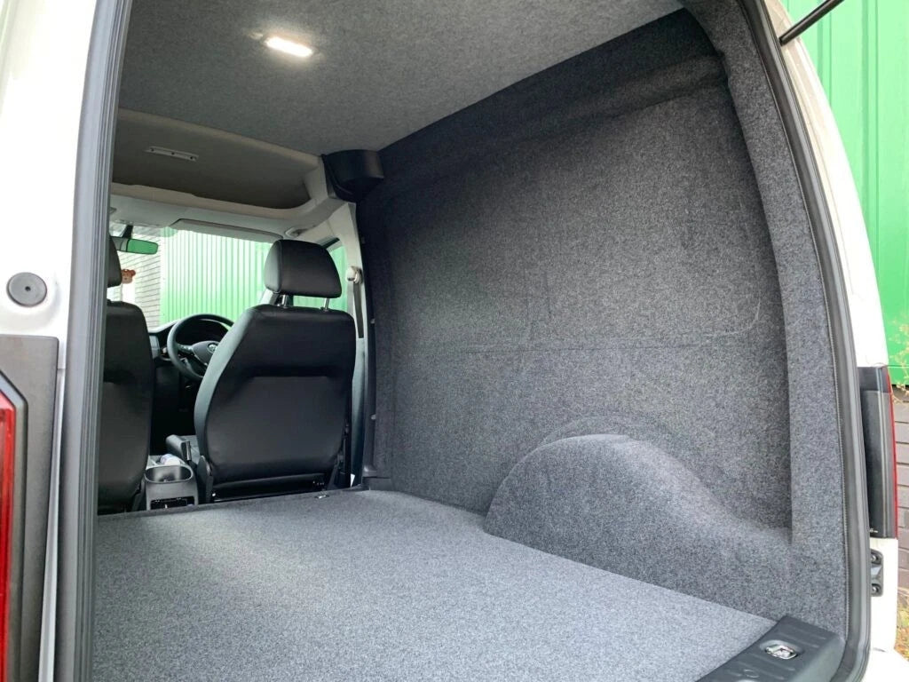 Van interior with grey carpet lining on the wall, wheel arch and floor