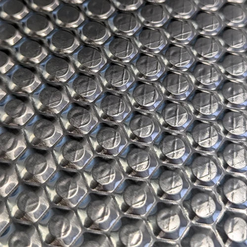 Close-up of the raised circular embossing on a sound deadening sheet's foil face